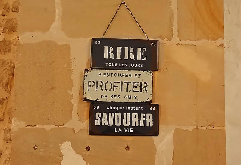 mur intérieur d'un restaurant à Poitiers avec 3 plaques de nom de rue : la rue 'rire', la rue 'profiter de ses amis et la rue 'savourer'